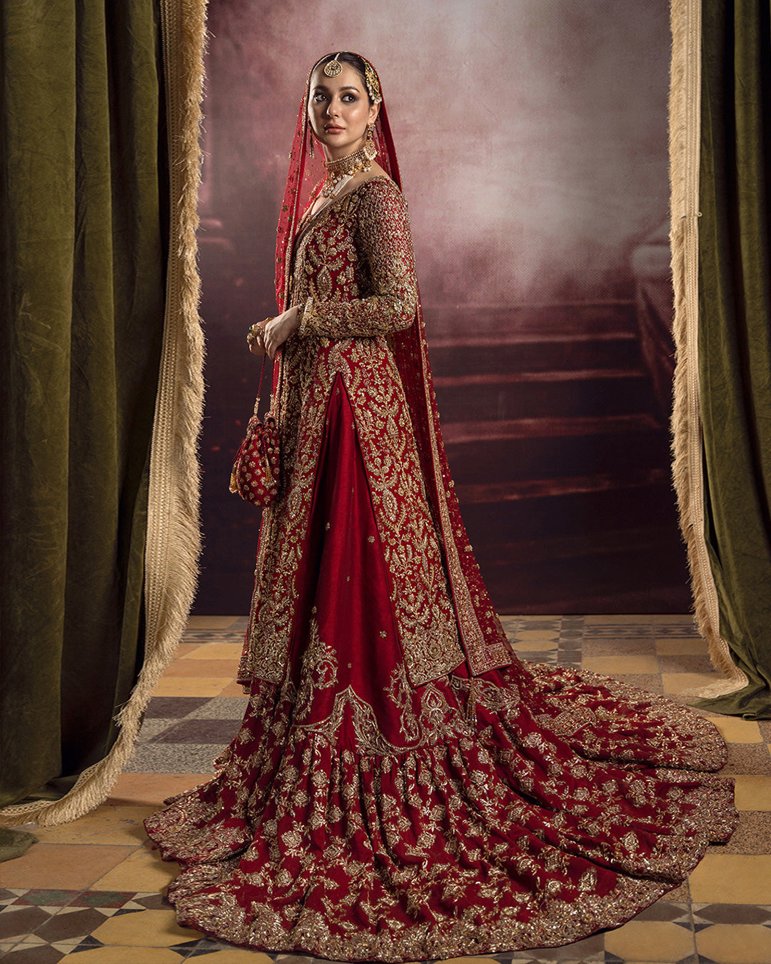 Faiza Saqlain Roushana crimson red bridal outfit with intricate gold-toned embroidery at Zenni’s Atelier