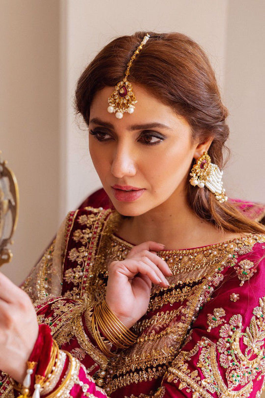 MNR Mursel luxury maroon bridal lehenga featuring elaborate gold embroidery and traditional ornamental motifs at Zenni’s Atelier